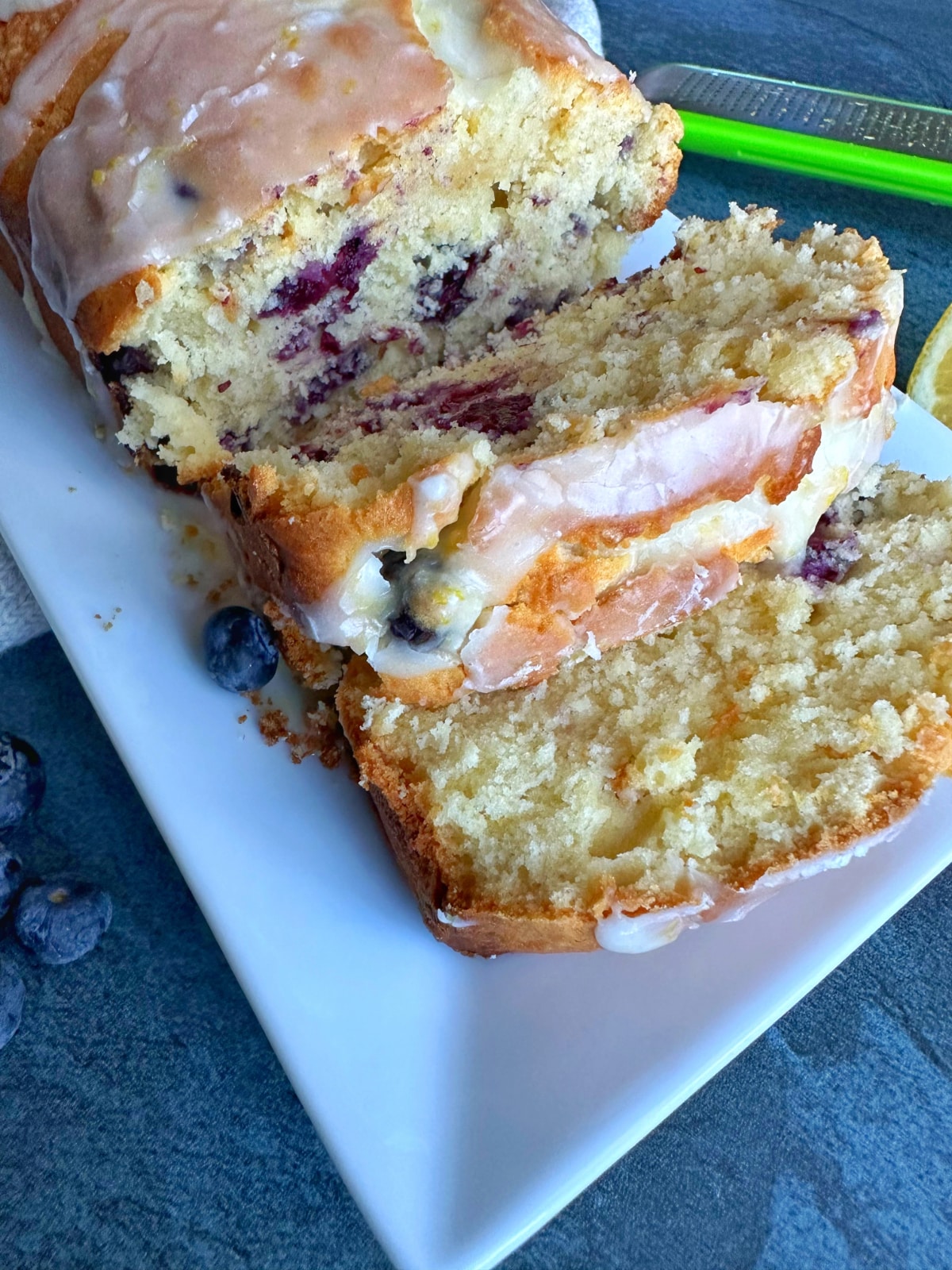A lemon blueberry loaf cake with lemon glaze, with two slices cut out.