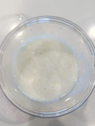 A clear bowl containing lemon juice and milk to create homemade buttermilk.