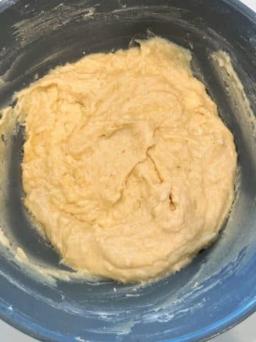 A grey mixing bowl filled with pale yellow cake batter.