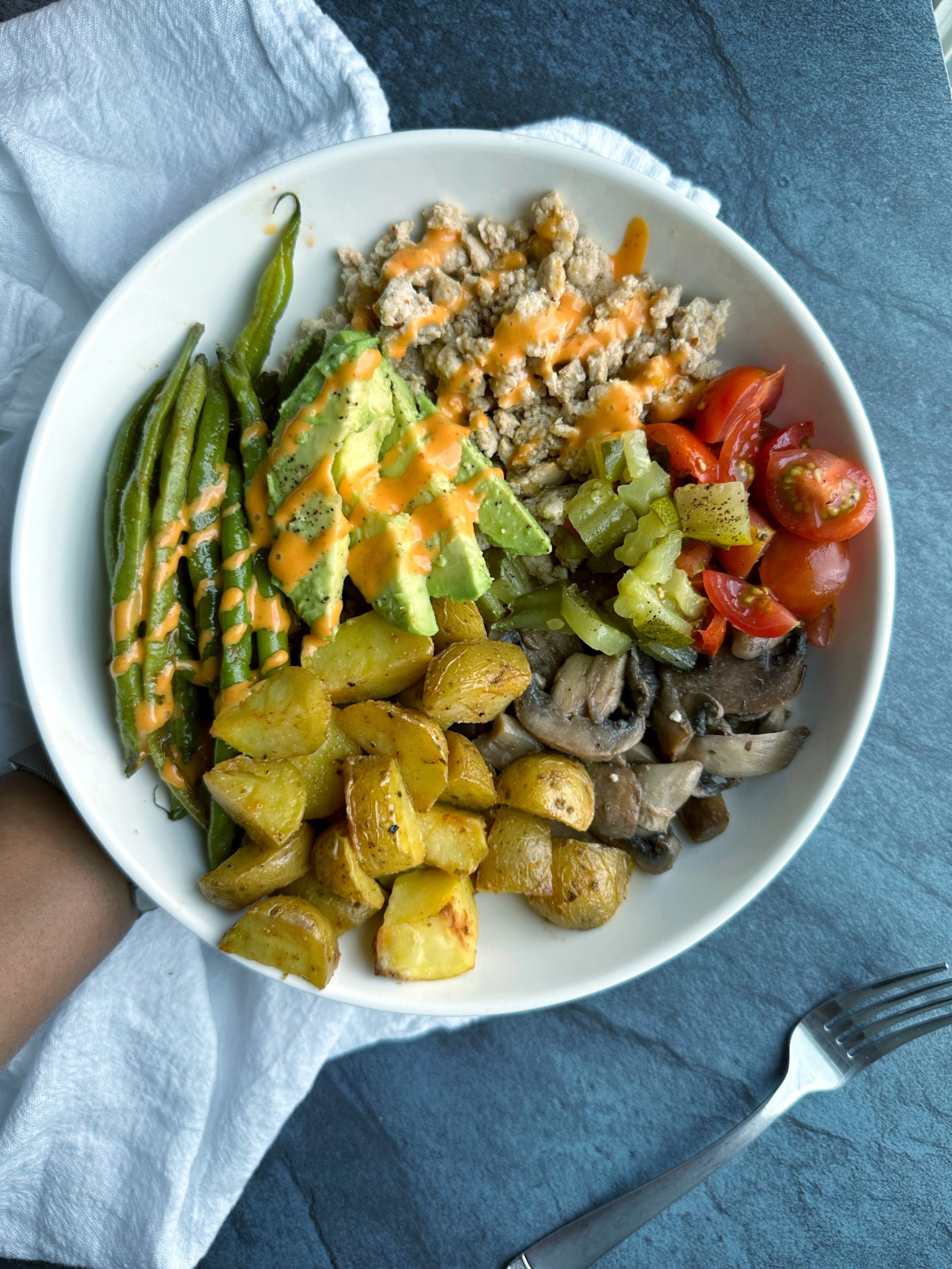A hand holding a homemade chicken burger bowl.