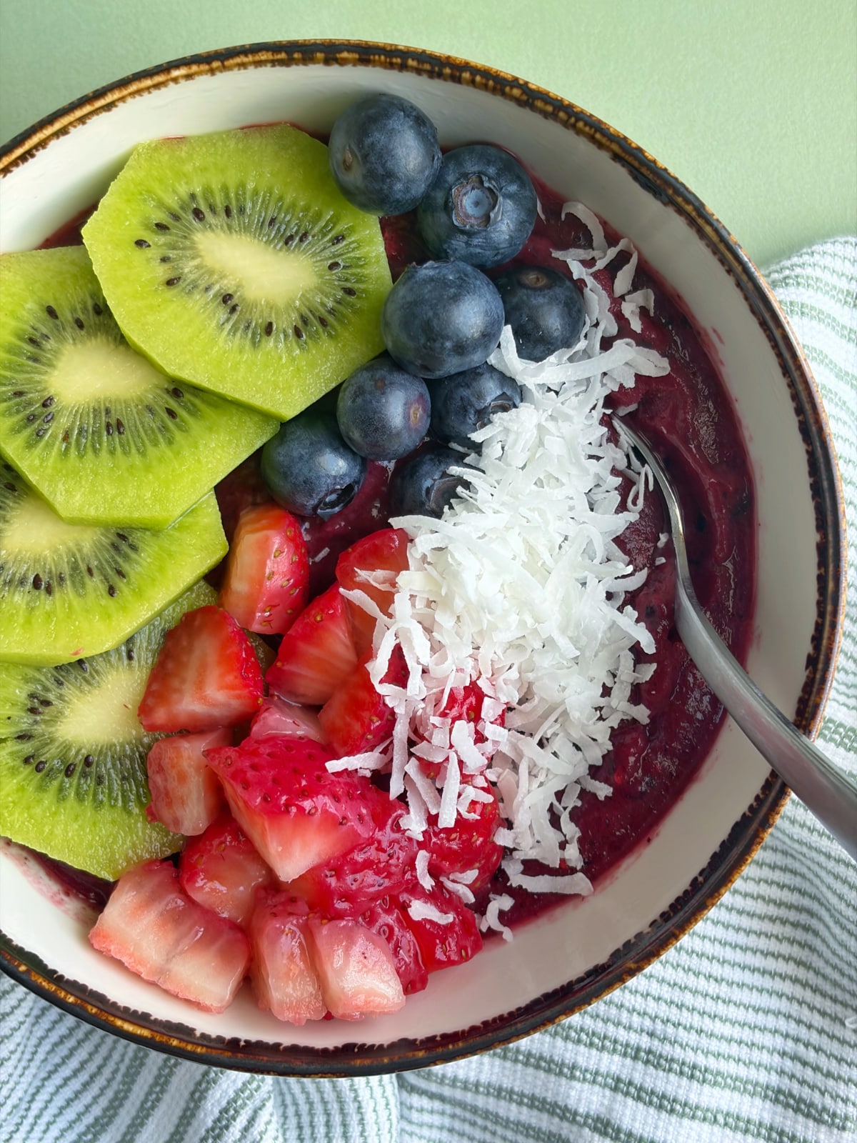 A shot of a purple, mixed berry smoothie bowl with fresh fruit and coconut on top.