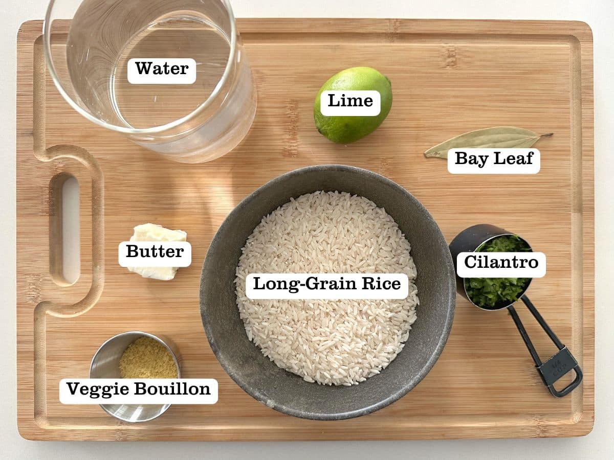 A wooden board containing bowls of ingredients for cilantro-lime rice, including butter and bouillon seasoning.