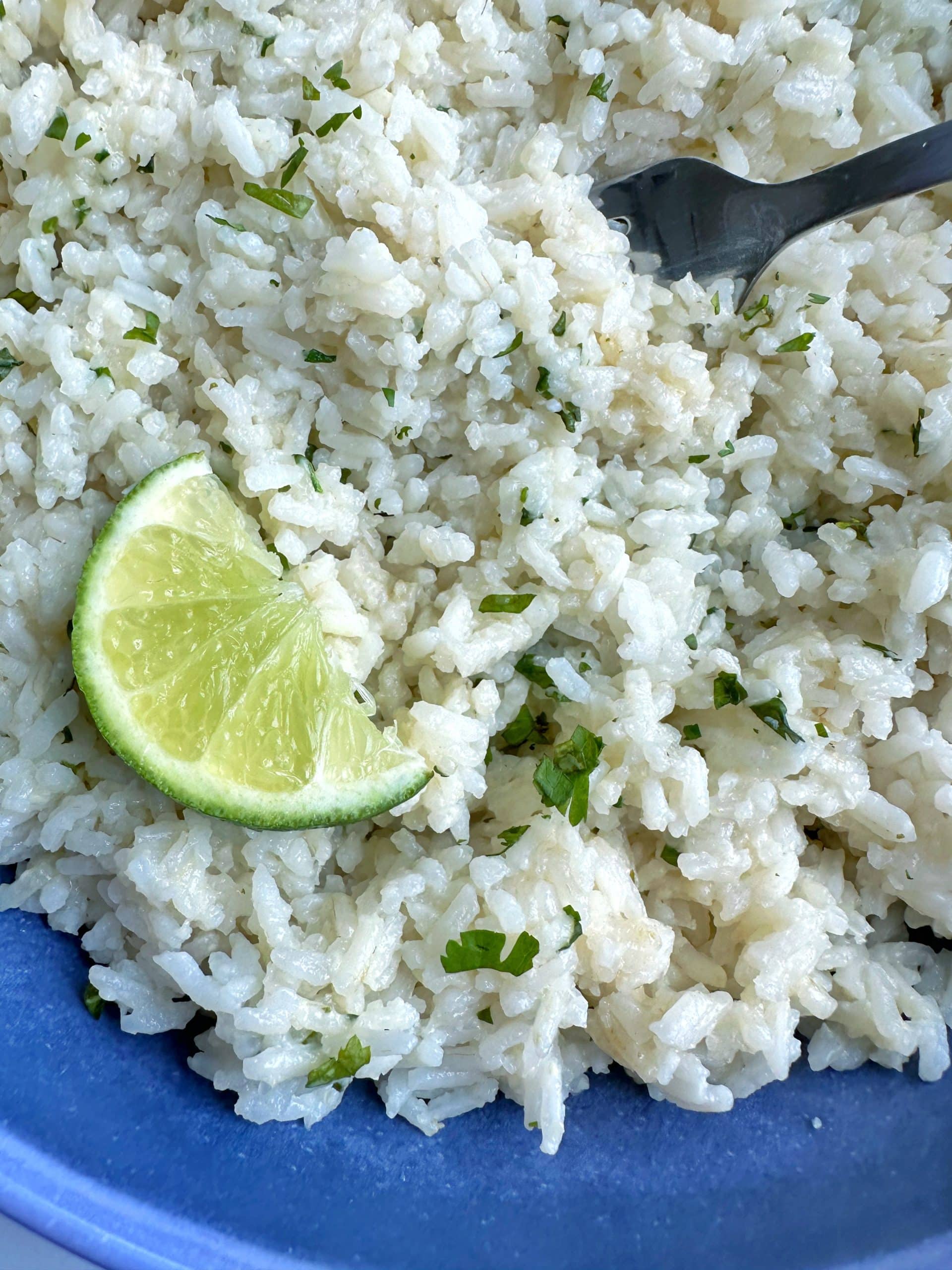 A bowl of copycat chipotle cilantro-lime rice with a lime wedge on the side.