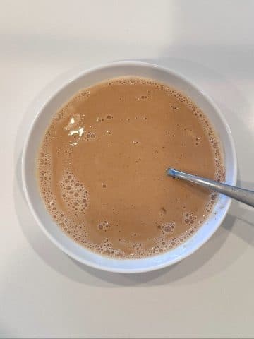 A shallow bowl filled with French toast dipping liquid, with a fork sticking out of it.