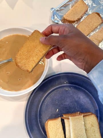 A hand showing a freshly dipped piece of brioche bread.