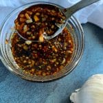 A bowl of Garlic Honey Soy Sauce with a bulb of garlic in the background.