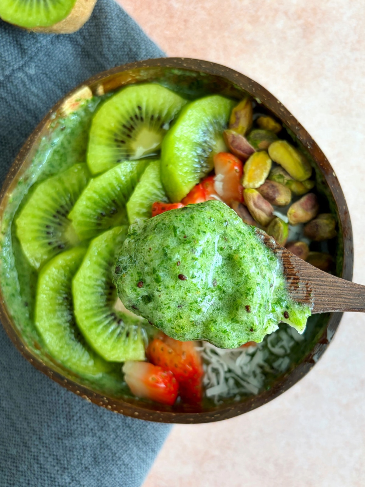 A spoonful of green smoothie suspended over the remainder of the bowl below.