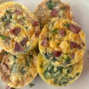 A shot of multiple egg bites or mini frittatas stacked on a plate.