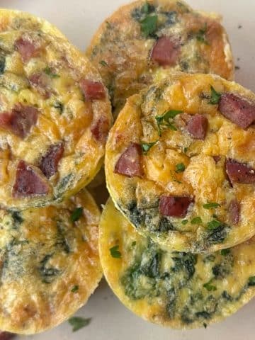 A shot of multiple egg bites or mini frittatas stacked on a plate.