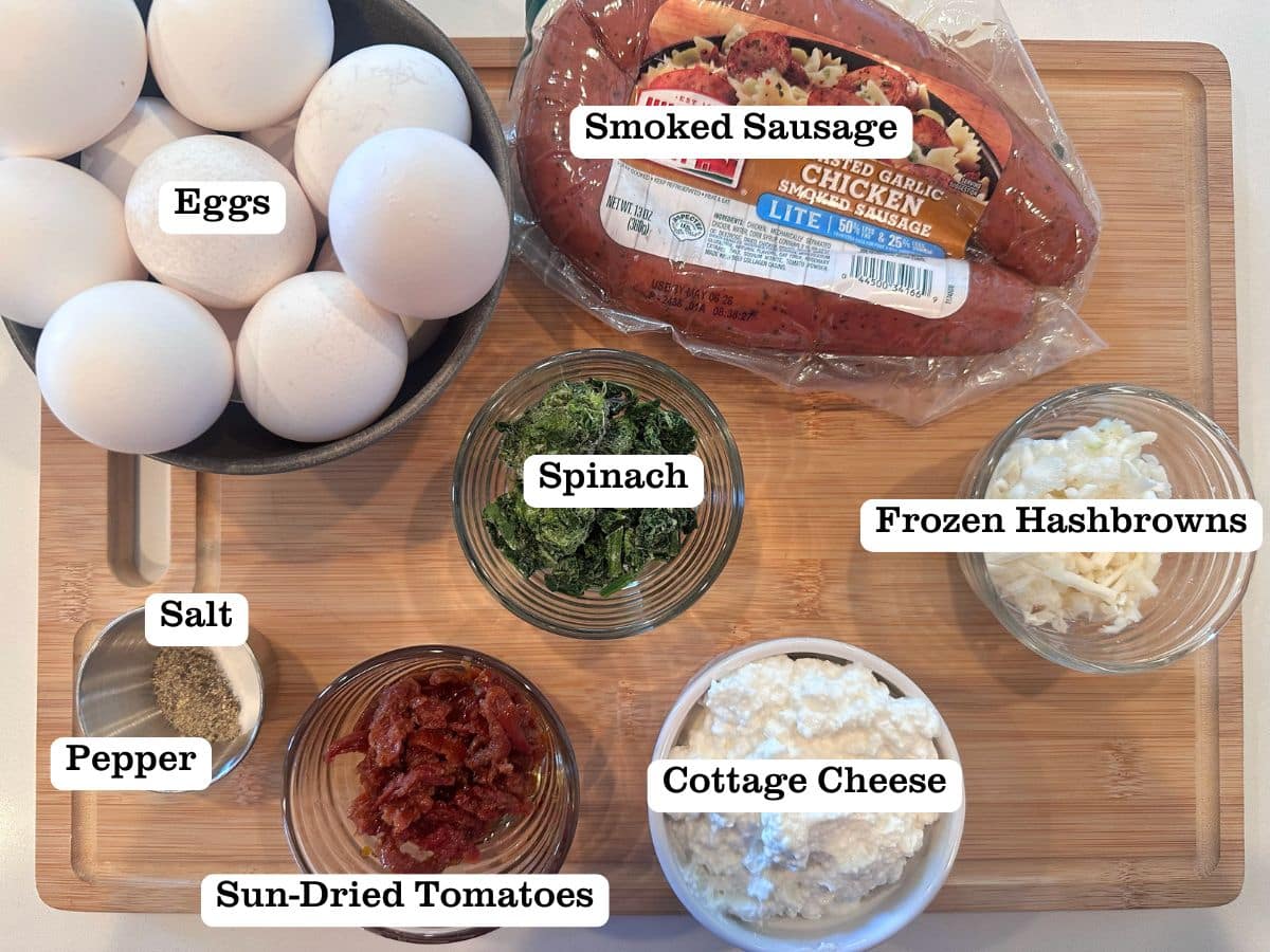 A wooden board containing ingredients for homemade egg bites, including sausage, cottage cheese, and spinach.