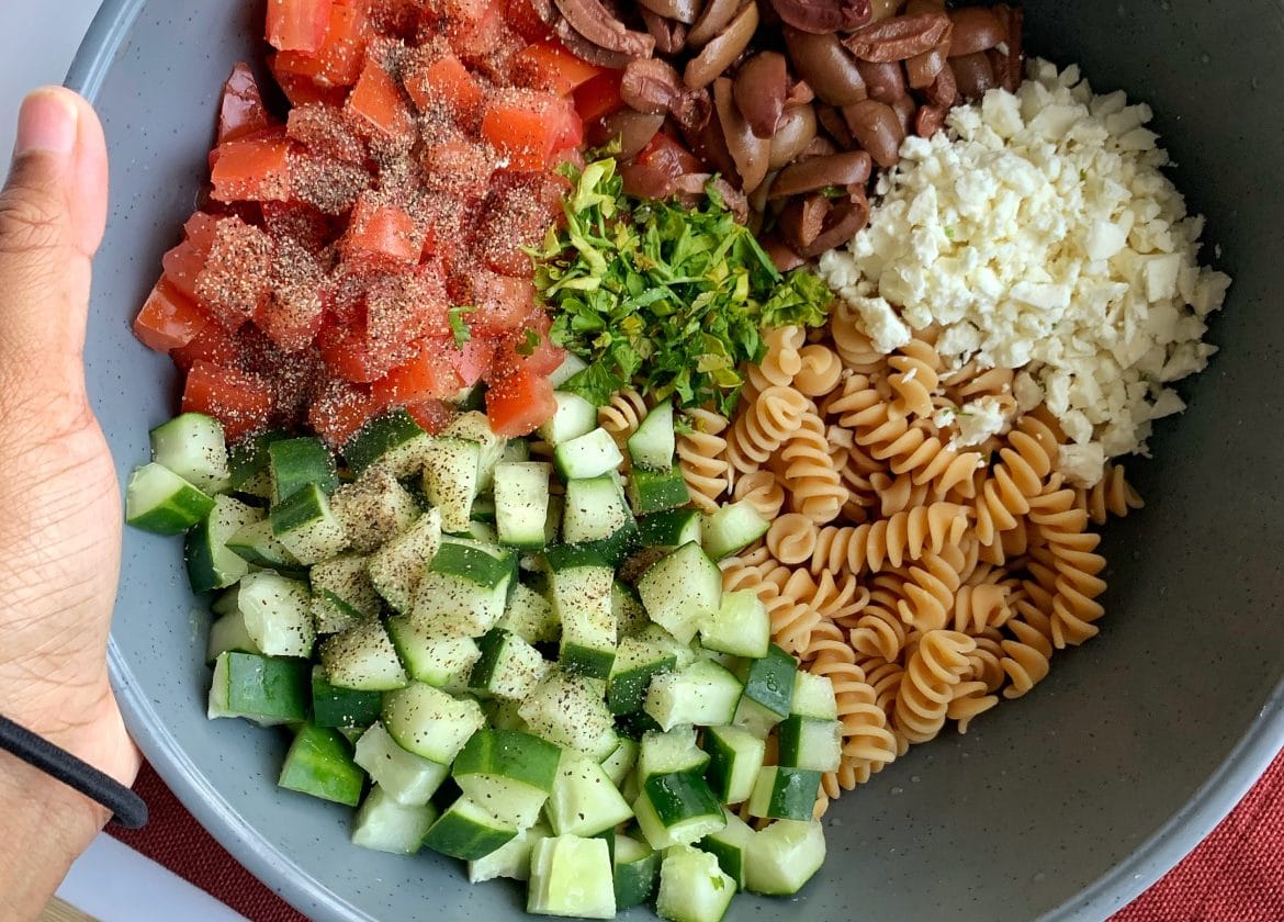 Ingredients for high-protein Mediterranean/Greek Pasta Salad in a large bowl.