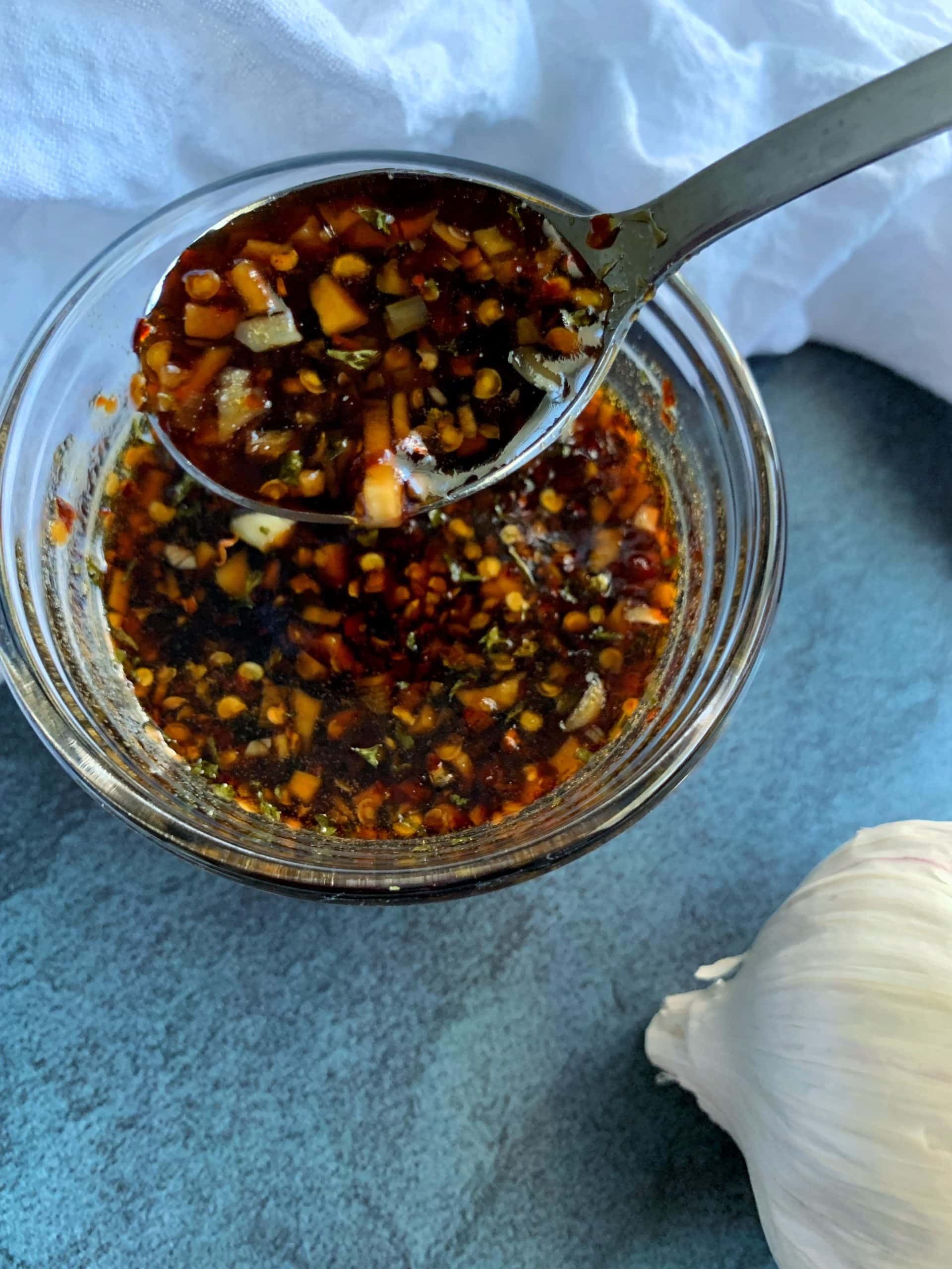 A bowl of Garlic Honey Soy Sauce with a bulb of garlic in the background.
