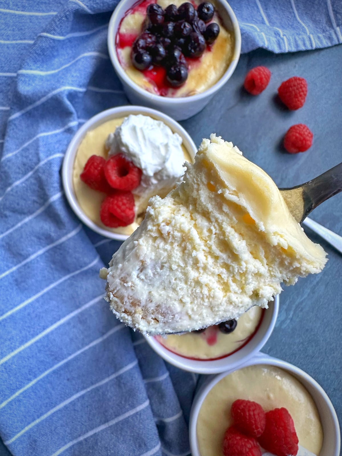 A spoonful of mini cheesecake with the other ramekins in the background.