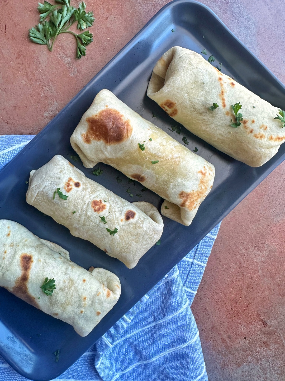 A tray of four breakfast burritos made with homemade tortillas.