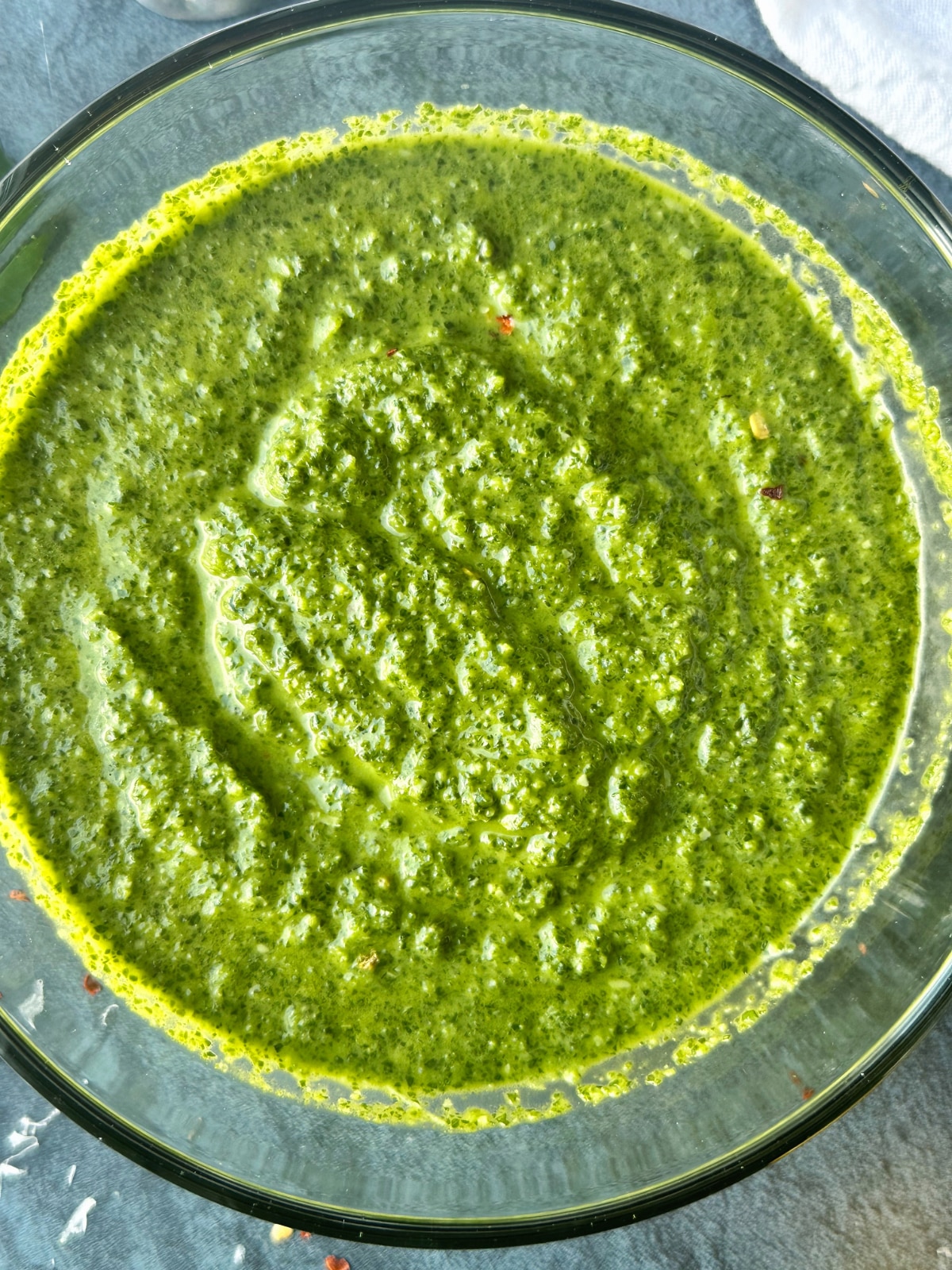 A glass bowl containing spinach-basil pesto.