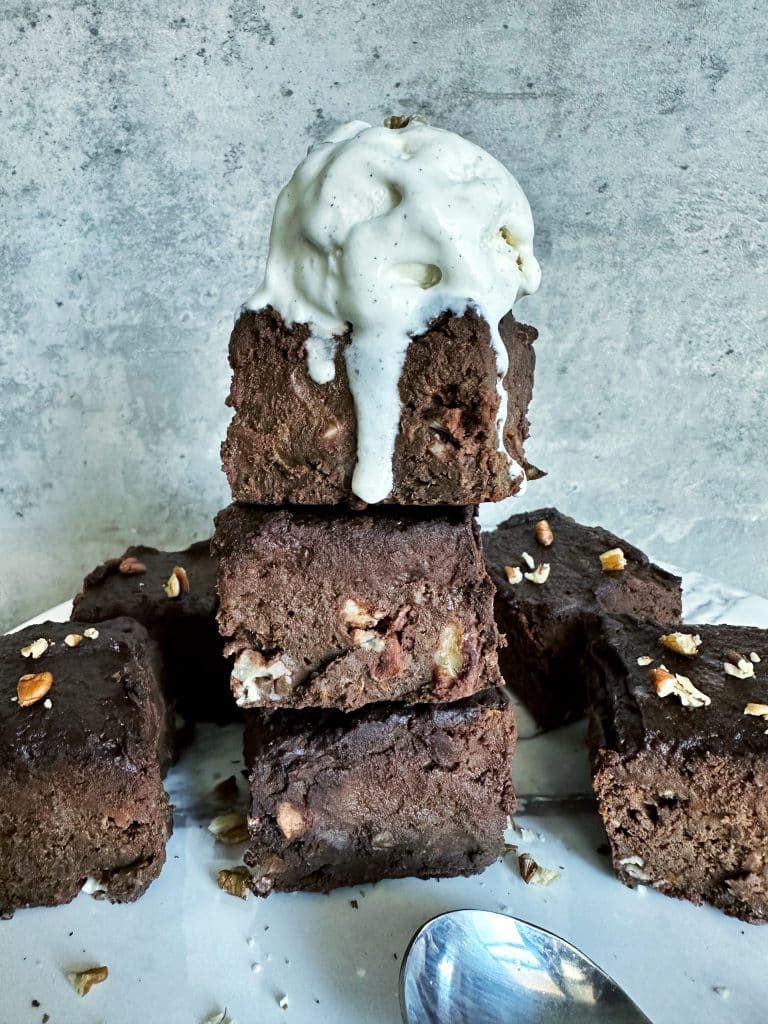 A stack of fudge sweet potato brownies with a scoop of ice cream on top.