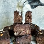 A spoon about to dig into a stack of fudge sweet potato brownies with a scoop of ice cream on top.