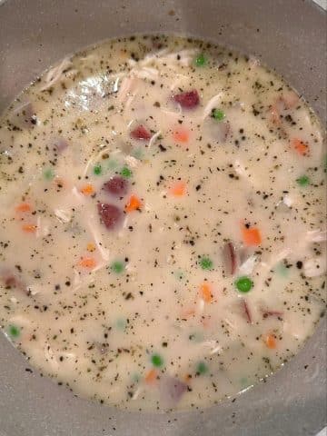 A pot filled with chicken pot pie soup and spices.