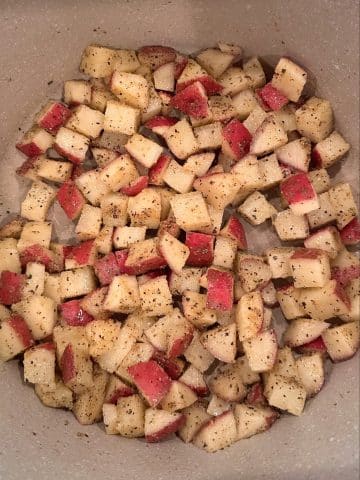 Seasoned diced potatoes sautéing in a Dutch oven.