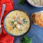 A bowl of non-dairy chicken pot pie soup with biscuits served on the side.