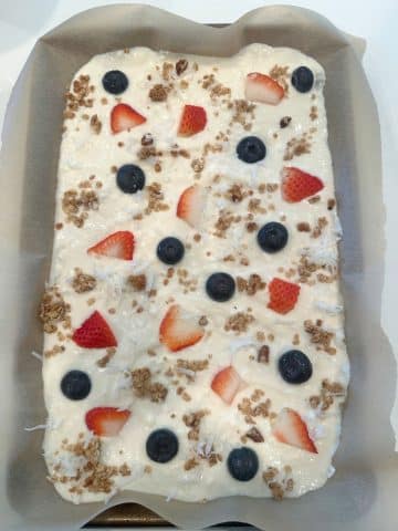 A parchment-lined tray with a layer of yogurt, topped with berries and oats.
