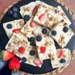 A tray of yogurt bark with fruit and granola, cut into squares.