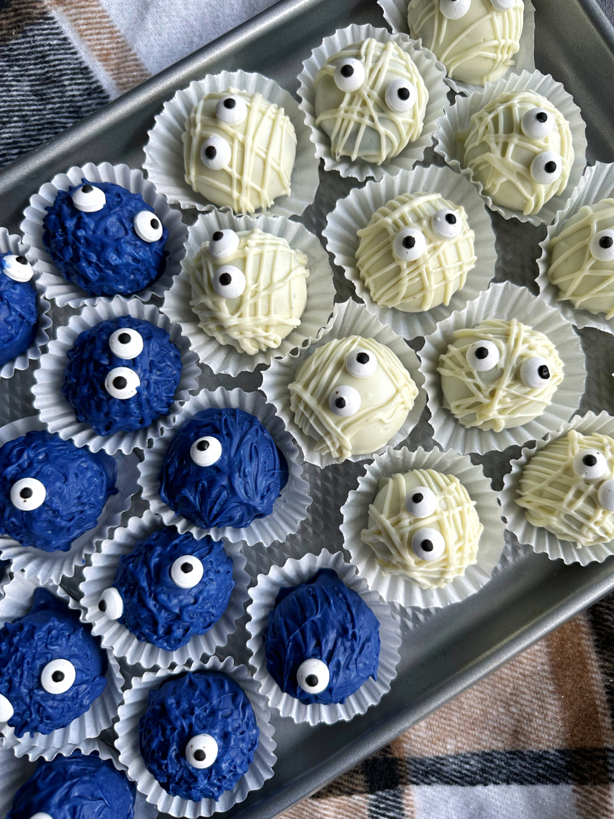 A silver tray of Oreo truffles that are Halloween-themed - decorated like mummies and blue monsters.
