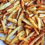 A parchment-lined baking tray of crispy oven-baked French fries.