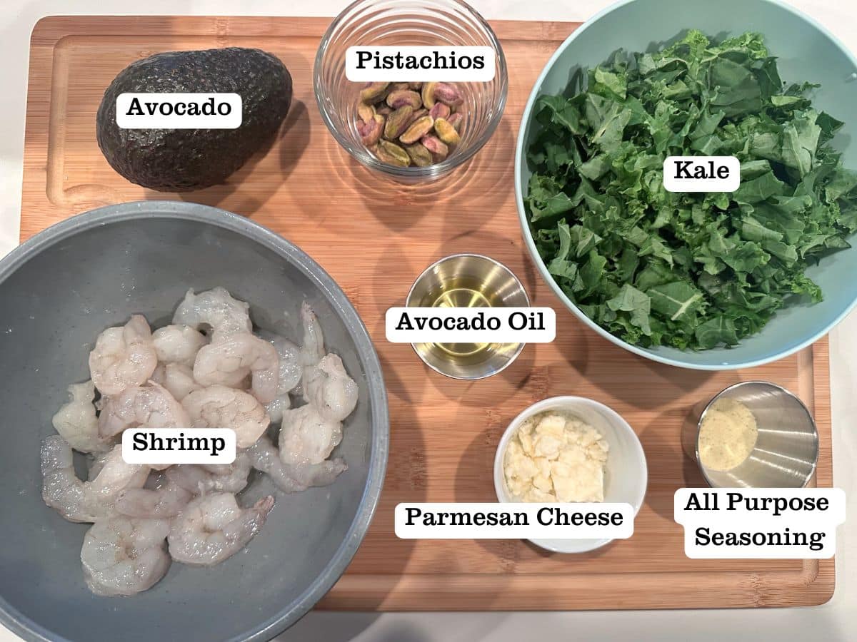 A wooden board containing ingredients for shrimp salad.