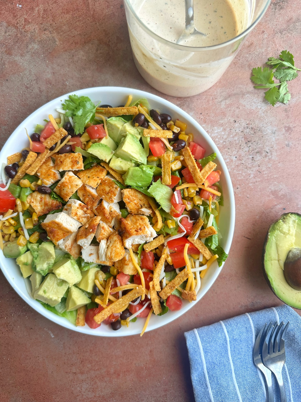 A chicken salad on romaine with ingredients like avocados and tortilla strips.