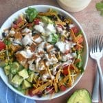 A bowl of southwest chicken salad drizzled in salad dressing.