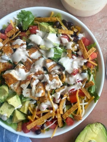 A bowl of southwest chicken salad drizzled in salad dressing.
