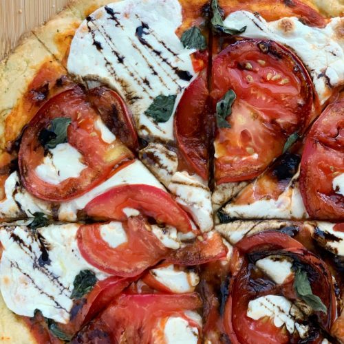 caprese pizza with balsamic glaze, sliced