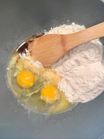 A mixing bowl filled with two eggs, vanilla extract, and cake mix.