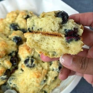 A blueberry drop biscuit cut in half, being held by a hand.