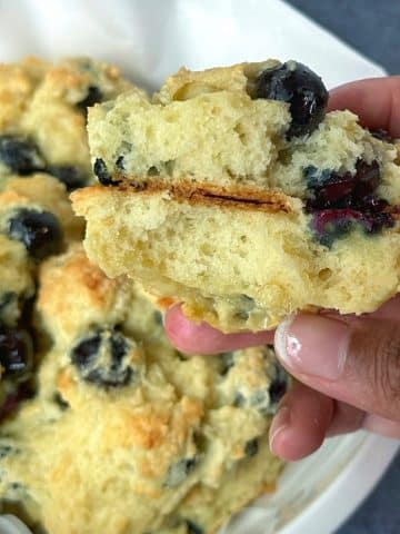 A blueberry drop biscuit cut in half, being held by a hand.