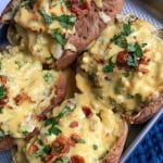 A pan of Broccoli Cheddar Loaded Stuffed Baked Potatoes with homemade cheese sauce on top.