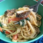 A bowl of jerk chicken alfredo with a fork showing off a bite.