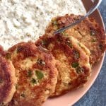 A plate of canned salmon patties over Cajun grits.