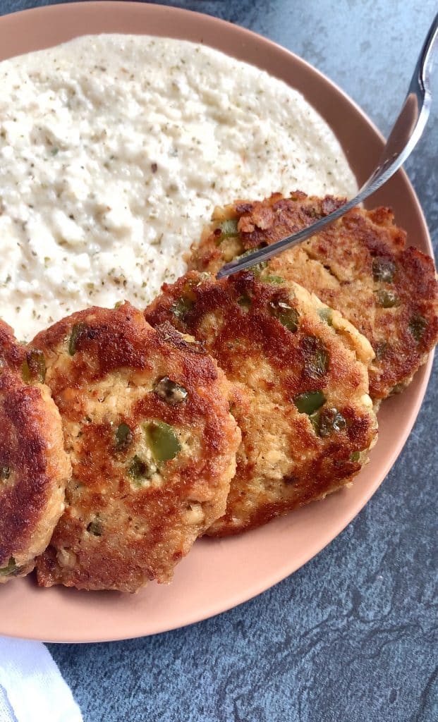 A plate of canned salmon patties over Cajun grits.