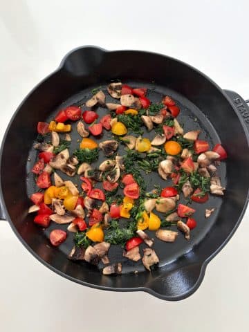 A cast iron skillet with sautéed vegetables.