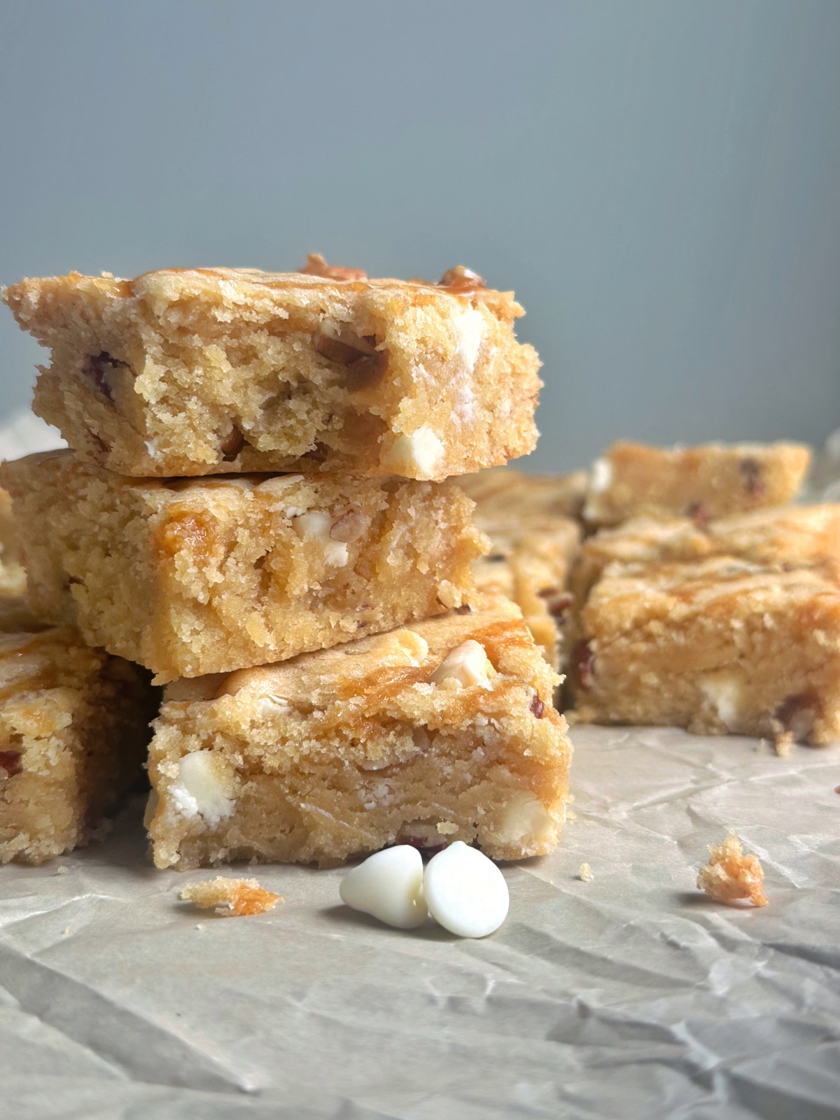 A stack of blondies with a bite taken out of the top, placed on parchment paper.