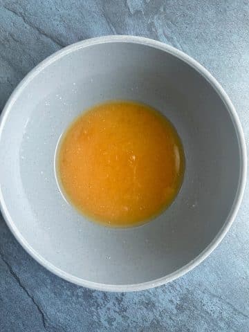 A mixing bowl containing a mixture of melted butter and brown sugar.