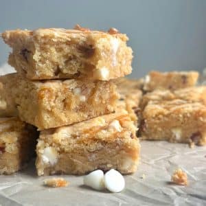 A stack of three brown sugar blondies on a crumpled piece of parchment paper.