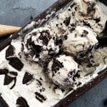 A pan of no-churn cookies and cream ice cream with 3 scoops placed on top.