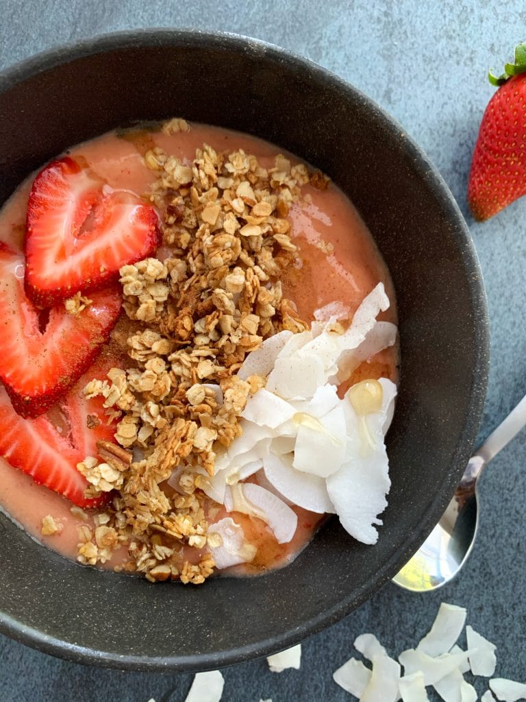 strawberry-mango smoothie bowl with coconut flakes, granola, and sliced berries