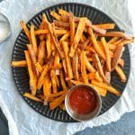 A plate of air fried sweet potato fries with a side of ketchup.