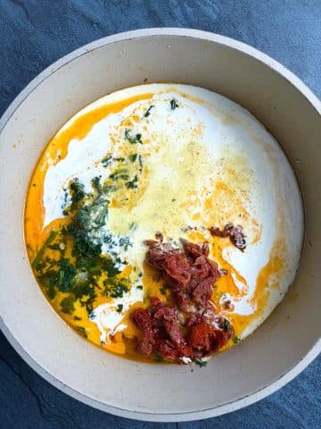 A skillet filled with a sun-dried tomato cream sauce.