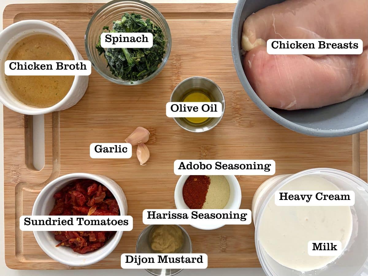A wooden board with containers of ingredients for cream sauce chicken.