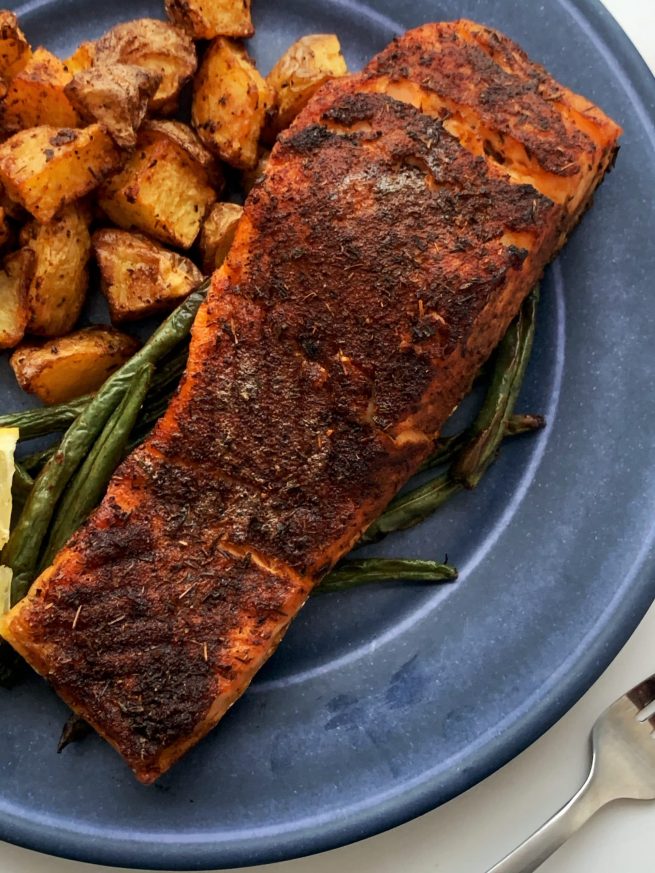 air fried blackened salmon on a blue plate with fried potatoes and green beans